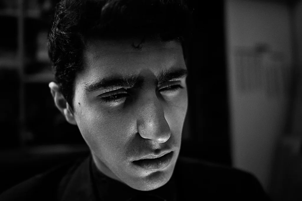 Porträt eines Mannes im Profil, Schwarzweißfotografie, dramatisches Seitenlicht, nachdenkliche Stimmung, minimalistische Komposition