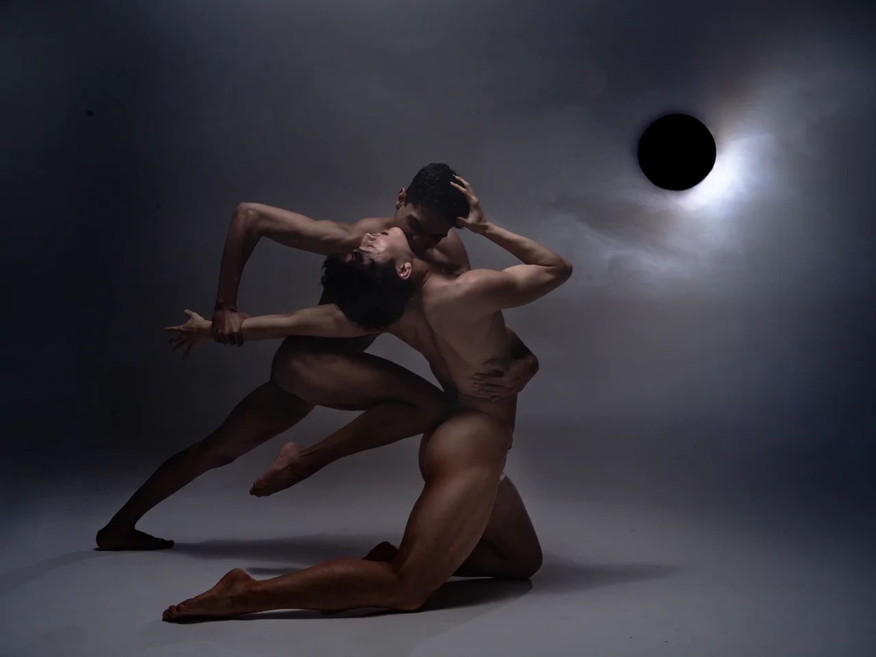 Two naked dancers in an artistic pose in front of a solar eclipse, dramatic light, editorial photography